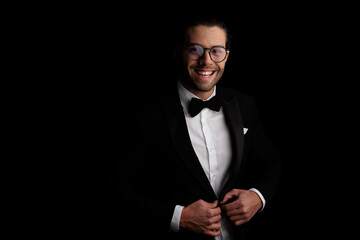 portrait of handsome young groom with glasses unbuttoning tux