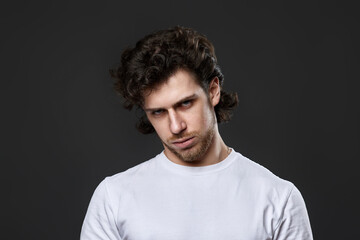 Obraz premium young upset curly man in white t-shirt
