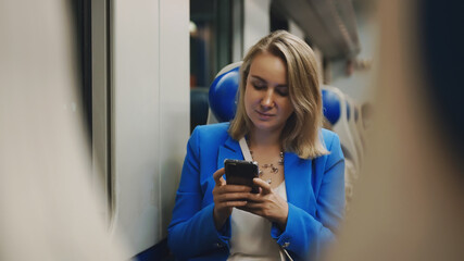 Woman in business suit with phone travelling by the train.