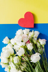Flowers composition an red heart,eustoma flowers on blue yellow background. Flat lay, top view.Copy space. Valentine's Day, wedding composition
