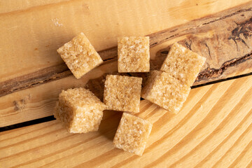 Several brown sugar cubes, close-up, on a wooden table, macro, top view.