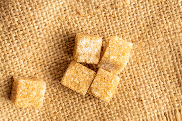 Several cubes of brown sugar, close-up, on a jute fabric, top view.