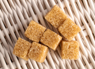 Several cubes of brown sugar, close-up, on a tray woven from a vine, top view.