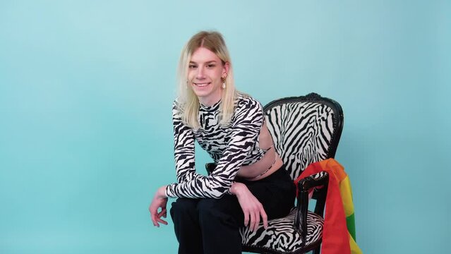 Youth transvestite LGBT with Rainbow flag sits on color background. Gender expression pride and equality concept