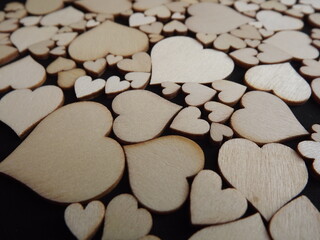 Wooden hearts on a black background as a postcard for the holidays