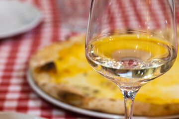 Glass of white wine stands on a table in an Italian restaurant, close up