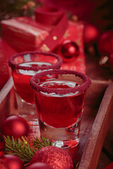 Cranberry vodka shot and Christmas decorations on wooden background. Winter holidays concept.