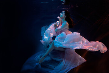 Gorgeous sensual model, ballerina swimming underwater in fluttering dress. Soft blurred focus.