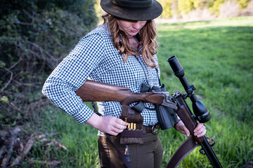Jagdausübung - Junge Jägerin ladet ihr Jagdgewehr.