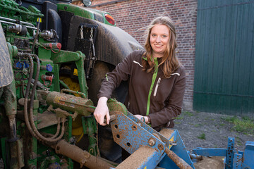 Junge Landwirtin prüft ob das Landwirtschaftliche Gerät sicher am Traktor befestigt ist.