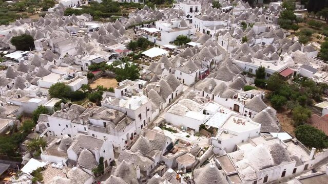 Aerial drone footage of Alberobello, Puglia, Italy. Fly over the traditional whitewashed, conical roof (trulli) UNESCO world heritage site, landmark tourist destination from above.