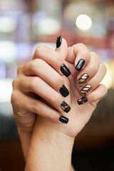 black and gold manicure, hands on a blurred background. Close-up hands of a young woman with a...