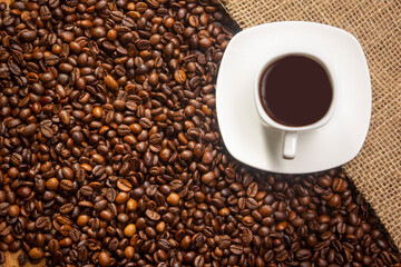 Coffee break background. Hot coffee in cup and roasted coffee beans on a wooden table. Copy space
