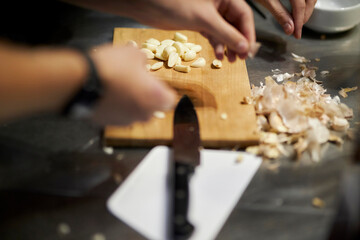 chef cuts garlic cloves on a cutting board. Chef cuts garlic on wooden board in the kitchen.