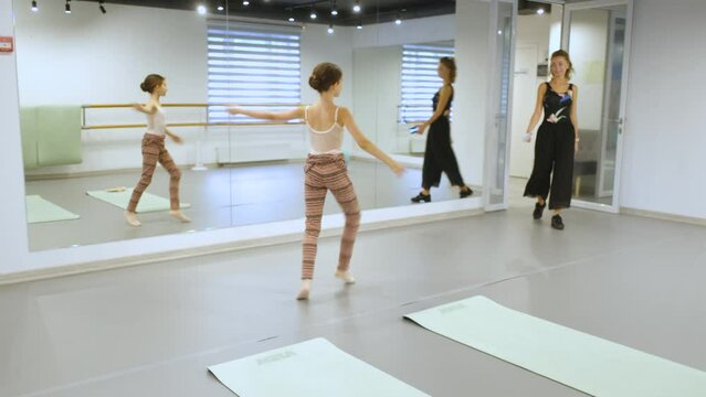 a girl is dancing ballet in the classroom when the teacher enters