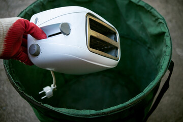 Throw old household appliances in the trash.A hand throws a sandwich toaster into a bucket.Disposal...