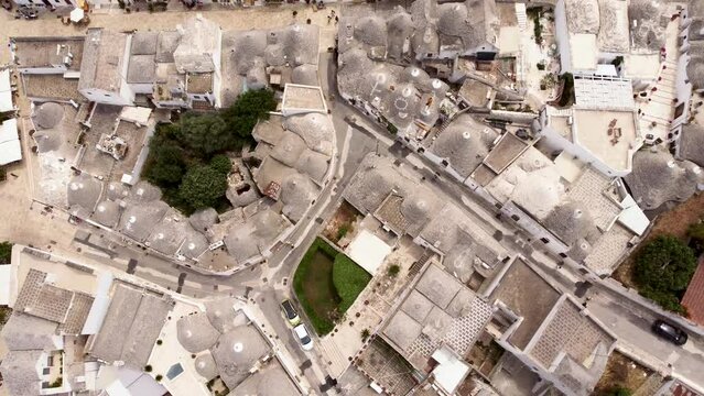 Aerial drone footage of Alberobello, Puglia, Italy. Top down reveal scene of the traditional whitewashed, conical roof (trulli) UNESCO world heritage site, landmark tourist destination from above.