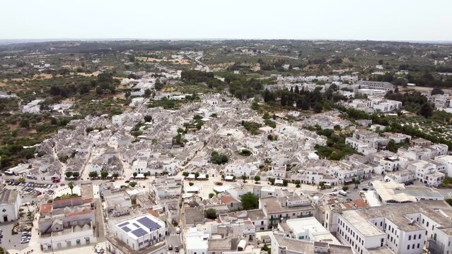 Aerial drone footage of Alberobello, Puglia, Italy. Establish scene of the traditional whitewashed, conical roof (trulli) UNESCO world heritage site, landmark tourist destination from above.
