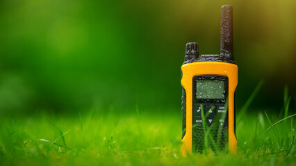 An ornamental portable walkie-talkie in the green grass in summer. Moisture protection on the...