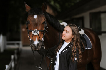 Portrait of smiling female jockey standing by horse near stable