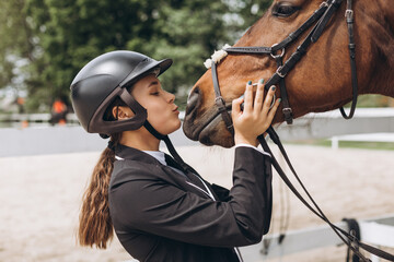 Beautiful brunette girl kissing her horse before riding. Equestrian sport