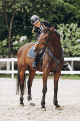 Young woman in special uniform and helmet riding horse. Equestrian sport - dressage