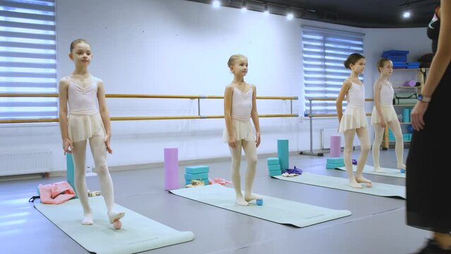girls at the ballet lesson doing a leg warm-up