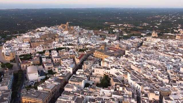 Aerial drone footage of Ostuni - La Citta Bianca (white city), Puglia, Italy at sunset. Establish scene of Cathedral, main square,the medieval historic old town landmark tourist destination from above