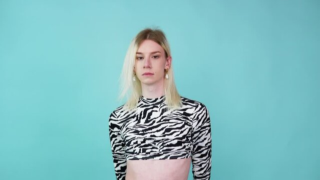 Young transvestite poses in studio on a blue background