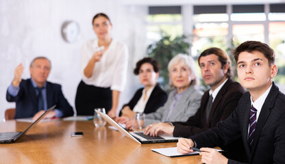 Plakat Woman and man sitting at table beside her colleagues during meeting in conference room