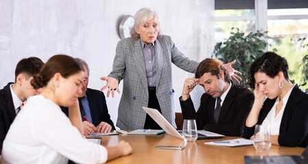 Elderly female boss expresses dissatisfaction with the work of the top managers team