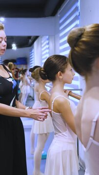 vertical video, girls are engaged with the teacher at the ballet barre