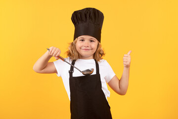 Funny kid chef cook with kitchen ladle, studio portrait. Kid chef cook prepares food on isolated...