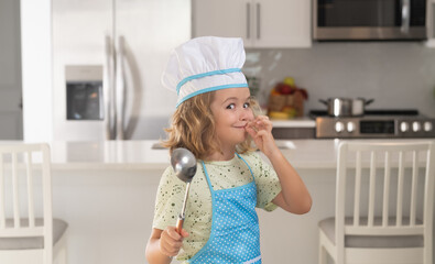 Kid chef cook wearing cooker uniform and chef hat preparing food on kitchen. Cooking, culinary and...