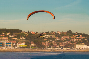 leisure motorized paragliding activity surfing the beach and the waves of the sea and the ocean at sunset on a beautiful sunny day in Asturias. 