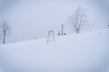 People go up the ski lift on the mountain side through the fog