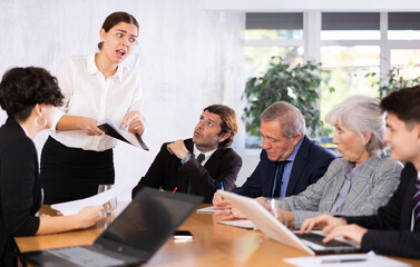 Female corporate worker expressively speaking at team briefing, disagreeing, arguing, blaming others