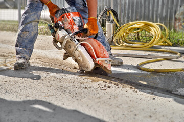 Construction worker cutting concrete foundation using a cut-off saw. Profile on the blade of an...