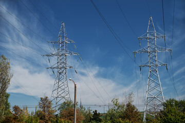 Tower with high-voltage energy transmission wires against the blue sky. High-voltage tower. Electrical wires and fuses. Energy business. Energy industry. Import and export of energy.