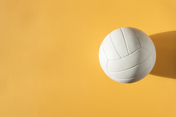 White volleyball leather ball on yellow background. Top view. Game equipment horizontal sport theme...