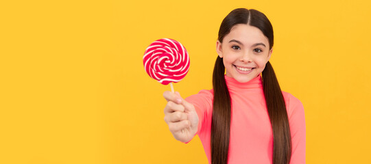 happy teen girl with lollipop candy on stick on yellow background, candy shop. Teenager child with...