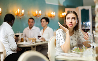 Elegant upset woman is expecting man for dinner in luxury restaurante