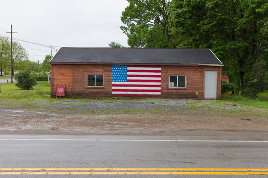 A Sale Today A board and an American flag painted on empty building on a street in a small town.