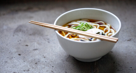 A bowl of noodles, vegetables and broth and a set of chopsticks.