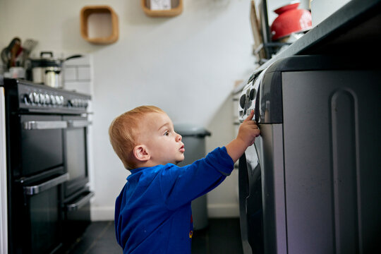 Toddler reaching up and touching appliance in kitchen