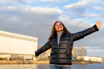 middle aged woman wearing winter clothes taking fun by a river