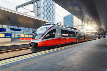 Red high speed train in motion on the railway station at sunset. Fast modern intercity train and...