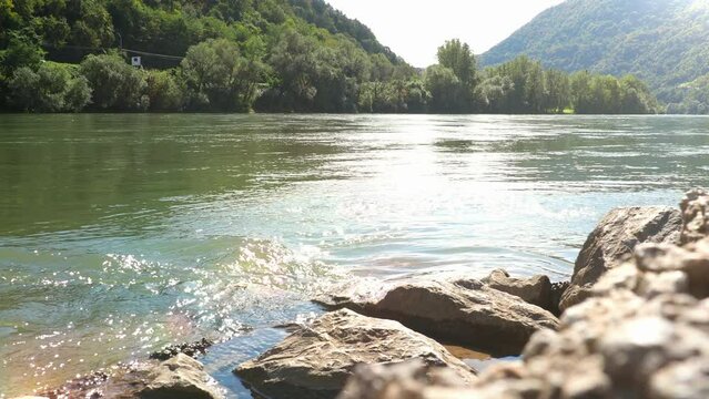 Drina river near Banja Koviljaca, view of the coasts of Serbia and BiH. The flow of water against mountains. The waves of the river meet at the rocky shore. Whirlpool of water. Sun rays