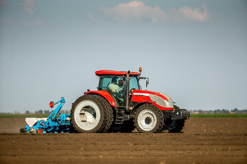 Agricultural worker planting soybean seeds with a tractor in a field
