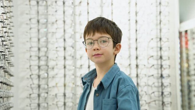 Portrait of a little boy in optics store in new glasses. Ophthalmology concept